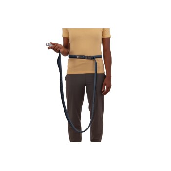 Eine Person in einem gelben Shirt und grauen Hosen hält eine Hundeleine, die an einem Hüftgurt befestigt ist, und zeigt eine freihändige Hundespazierlösung.