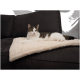 Eine entspannte Katze liegt auf einer weichen, cremefarbenen Decke auf einer dunklen Couch und zeigt ihr weißes und graues Fell.