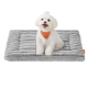 Kleiner weißer Hund mit orangefarbenem Halstuch sitzt auf einem grauen Plüsch-Haustierbett mit einem orangefarbenen Etikett.