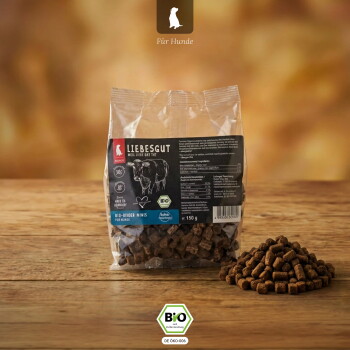 Klarsichtbeutel mit LIEBESGUT Hundesnacks (Für Hunde) mit einem Haufen braunem Kibble und Bio-'BIO'-Siegel auf einem Holztisch