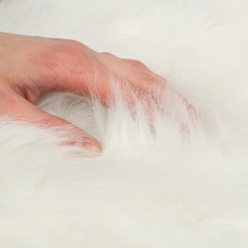 Eine Hand berührt sanft weiches, flauschiges weißes Fell und zeigt dessen Textur und Komfort.