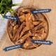 Premium-Hundeleckerlis auf einer Holzoberfläche, die verschiedene Stücke von Trockenfleisch mit einer grünen Pflanze im Hintergrund zeigen.