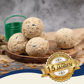 Vier natürliche Tierfutterbälle auf einem Holzbrett, mit einem grünen Eimer dahinter und einem Abzeichen "Beste Qualität - 15 Jahre."