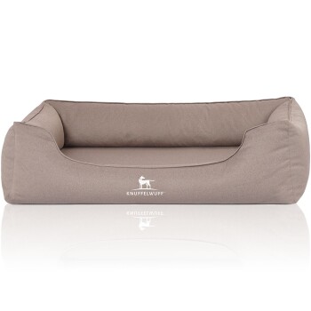 Ein plüschiges, beiges Hundebett mit erhöhten Seiten und einem weichen Kissen, das das Logo "KNUFFELWUFF" prominent auf der Vorderseite zeigt.