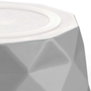 Nahaufnahme einer weißen, geometrischen Futterschüssel für Haustiere mit einem glatten, runden Rand und einer strukturierten, facettierten Oberfläche.