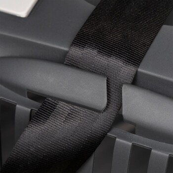 Nahaufnahme einer grauen Haustiertrage mit einem schwarzen Riemen, der um den Griff gesichert ist, was die Haltbarkeit und Sicherheit für den Transport von Haustieren betont.