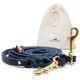 Eine geflochtene marineblaue Hundeleine mit goldenen Verschlüssen, neben einem beigen Zugbeutel mit dem Logo "FREUDENTIER" platziert.