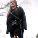 Eine Person in einem schwarzen Outfit steht im Freien mit einem kleinen Hund zu ihren Füßen und zeigt eine lässige, haustierfreundliche Umgebung.