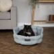 Eine schwarz-weiße Katze, die in einem hellblauen Scruffs-Haustierbett entspannt, in einem gemütlichen Wohnzimmer mit einem grauen Sofa und Holzdekoration.