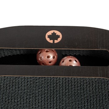 Eine Nahaufnahme einer Aufbewahrungseinheit für Haustierspielzeug mit zwei rosa, perforierten Bällen und einer Holzoberfläche mit einem Ahornblatt-Logo.