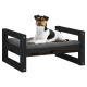 Ein schwarzes Holz-Hundebett mit einem grauen Kissen, auf dem ein kleiner Hund bequem liegt.
