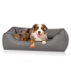 Ein glücklicher Australian Shepherd Hund, der in einem grauen Haustierbett mit strukturiertem Design liegt, mit einem kleinen "KNUFFELWUFF" Etikett.