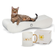 Eine gefleckte Katze entspannt sich auf einem gebogenen weißen Bett neben einer goldbeschrifteten "LOVE"-Tasse und einer "CanadianCat"-Geschenkbox.