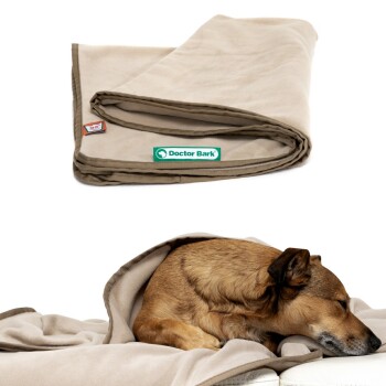 Eine gemütliche beige Haustierdecke von Doctor Bark, mit einem Hund, der bequem darin auf einem Sofa eingewickelt ist, und Wärme und Komfort zeigt.