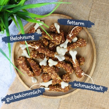Ein Holzbrett mit hundeförmigen Leckerlis, beschriftet auf Deutsch: "Belohnung", "fettarm", "gut bekömmlich" und "schmackhaft."