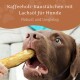 Ein brauner Hund kaut auf einem Kaffeestick, mit Text darüber: 'Kaffeholz-Kaustäbchen mit Lachsöl für Hunde' und 'Robust und langlebig.'