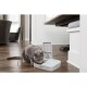 Ein grauer Kater, der aus einem weißen Petsafe-Automatenfutterspender in einem modernen Wohnzimmer mit Holzböden und natürlichem Licht frisst.