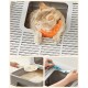 Eine flauschige Katze mit einem orangefarbenen Bandana sitzt am Eingang einer Katzentoilette, mit einer Schaufel für Katzenstreu und einem Reinigungswerkzeug, das darunter gezeigt wird.