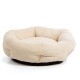 Ein plüschiges, rundes Haustierbett in einem sanften Beigeton mit einer strukturierten Oberfläche und einem schwarzen Boden, entworfen für Komfort.