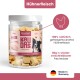 Bild einer Hand, die einen Hundesnack hält, mit Text, der '100% Huhn', '0g', 'Ohne Zucker oder Zusatzstoffe' und 'Ideal für Training & Belohnung' hervorhebt.