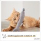 Eine verspielte orangefarbene getigerte Katze, die auf einem grauen fischförmigen Spielzeug mit einer Glocke kaut, mit dem Text "Spielzeug passend zu deinem Stil" am unteren Rand.