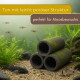 Drei gestapelte, moosbewachsene Tonröhren in einem bepflanzten Aquarium mit Fischen und Kies; deutscher Text über porösen Ton und Moosbewuchs.