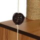 Gros plan sur un jouet en forme de balle tissée sombre suspendu à une corde blanche, reposant sur une surface en bois, avec un article en fibre naturelle texturée en arrière-plan.