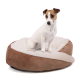 Ein kleiner, weiß-brauner Hund sitzt auf einem plüschigen, runden Hundebett mit einem weichen, cremefarbenen Innenraum und einem braunen Außenbereich.