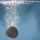 Ein schwarzer Haustierpflege-Schwamm, der in Wasser eingetaucht ist, umgeben von Blasen, vor einem blauen Hintergrund.