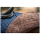 Nahaufnahme eines Sattelpads mit einer marineblauen, gesteppten Seite und einer weichen braunen Fleece-Seite, das auf dem Rücken eines Pferdes ruht.