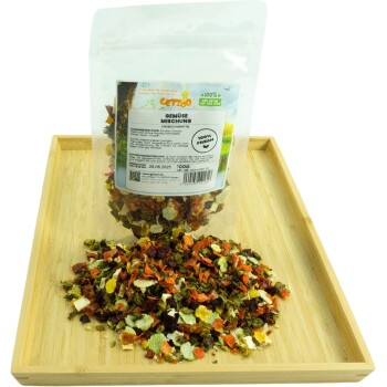 Getrocknete Gemüse-Mischung für Haustiere in einer klaren Tüte mit der Aufschrift "Gemüse Mischung" auf einem Holztablett, mit bunten Gemüsestücken, die herumliegen.