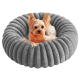 Kleiner Hund trägt ein orangefarbenes Bandana und liegt in einem runden, grauen, plüschigen Haustierbett aus einem Online-Tiergeschäft.
