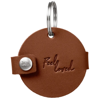 Runde braune Leder-Tiermarke mit Metall-Schlüsselring, mit der Prägung „Feel loved“ in Schreibschrift und silbernem Druckknopf.