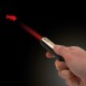 Ręka trzymająca czarno-złoty wskaźnik laserowy AniOne rzucający czerwony kształt ryby na czarnym tle.
