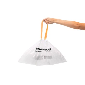Hand hält eine weiße Tasche mit orangefarbenen Griffen, beschriftet mit 'litter·robot by whisker'.
