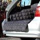 Ein schwarzer, gepolsterter Autositzbezug für Haustiere liegt im Kofferraum eines silbernen Autos und bietet Schutz für Reisen mit Haustieren.