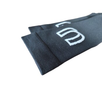 Schwarze Haussocken für Haustiere mit weißen gestickten Buchstaben, die eine Nahaufnahme des Stoffes und der Bündchendetails zeigen.