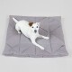Ein kleiner weißer Hund liegt bequem auf einem weichen, grauen Haustierbett mit einem gesteppten Design.