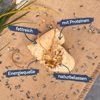 Eine ballförmige natürliche Haustierleckerei, die auf Deutsch beschriftet ist, umgeben von Sonnenblumenkernen auf einem Jute-Hintergrund.