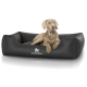 Ein hellbrauner Hund ruht auf einem schwarzen gesteppten Haustierbett, auf dem das Logo "KNUFFELWUFF" deutlich sichtbar ist.
