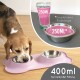 Ein Beagle-Hund, der aus einer pinken doppelten Futterschale frisst, mit einem Glas Wasser, das mit "250ML" beschriftet ist, und einer Schalenkapazität, die mit "400ml" angegeben ist.