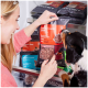 Eine Frau greift nach "Komfort-BARF Rind" Hundefutter, während ein Hund an der Tüte schnüffelt; andere Geschmäcker sind im Hintergrund sichtbar.