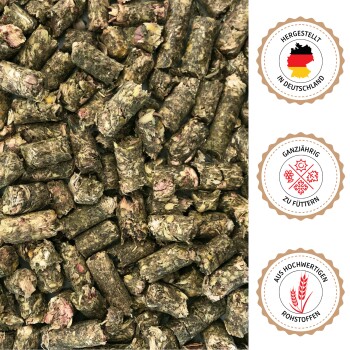 Nahaufnahme grünlich-brauner Tierfutterpellets mit deutschen Textabzeichen: „Hergestellt in Deutschland“, „Ganzjährig zu füttern“ und „Aus hochwertigen Rohstoffen“.