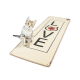 Ein verspieltes getigertes Kätzchen sitzt neben einer beigen Katzendecke mit dem Wort "LOVE" in fetten schwarzen Buchstaben und einem roten Ahornblatt-Design.