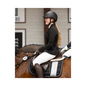 Ein Reiter in einer schwarzen Jacke und einem Helm sitzt auf einem braunen Pferd, trägt weiße Reithosen und braune Stiefel, mit einem Sattelpad, das "EQUINA" beschriftet ist.