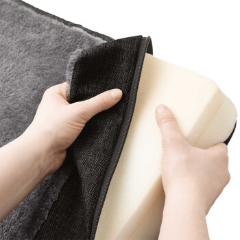 Eine Person hält einen Bezug für ein Haustierbett und öffnet den Reißverschluss, um ein weiches Schaumstoffeinlage im Inneren zu zeigen, das das abnehmbare Design des Bettes zeigt.
