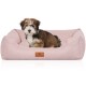 Ein kleiner, flauschiger Hund sitzt bequem in einem weichen, rosa Haustierbett mit einem braunen Lederetikett, auf dem "KNUFFELWUFF" steht.