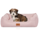 Ein kleiner, flauschiger Hund sitzt bequem in einem weichen, rosa Haustierbett mit einem braunen Lederetikett, auf dem "KNUFFELWUFF" steht.