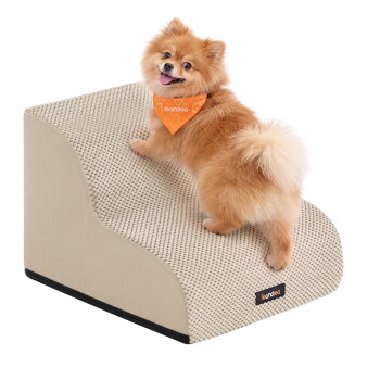 Corgi steigt eine graue, strukturierte Haustiertreppe zur Couch hinauf, trägt ein orangefarbenes Halstuch mit der Aufschrift 'leandrea'.