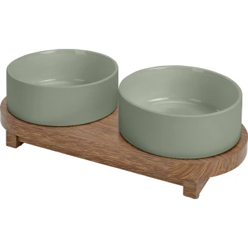 Zestaw misek na jedzenie i wodę dla zwierząt z dwoma jasnooliwkowymi ceramicznymi miskami na drewnianej podstawie.
